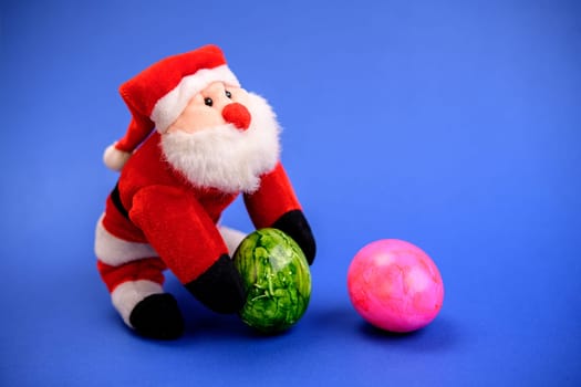 little santa claus with green and pink easter egg on blue ground