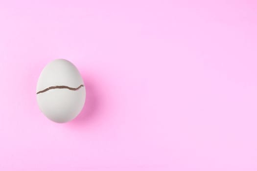broken egg with crack on pink ground
