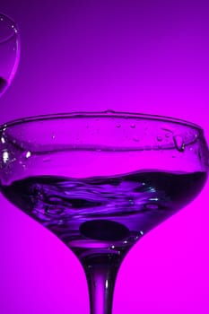 The wine stuffed glasse with cocktail standing on the table at studio. Vivid bright colored lighting. Trendy in 2018 Ultra Violet Light Bulb. Art decoration with tone of mystic color