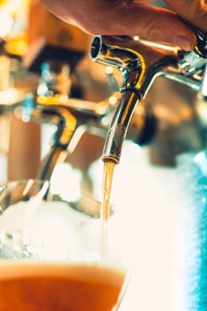 The beer taps in a pub. nobody. Selective focus. Alcohol concept. Vintage style. Beer craft. Bar table. Steel taps. Shiny taps. Glass of beer
