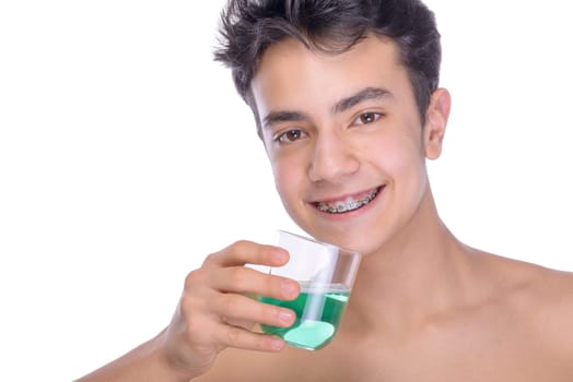 Cute teenager with white background, wearing braces on his teeth. Use mouthwash for oral hygiene.