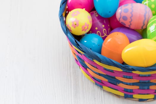 Easter eggs in basket on white wooden background