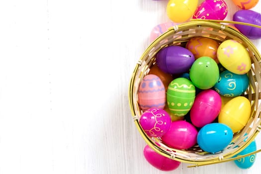 Easter eggs in basket on white wooden background