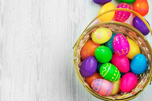 Easter eggs in basket on white wooden background