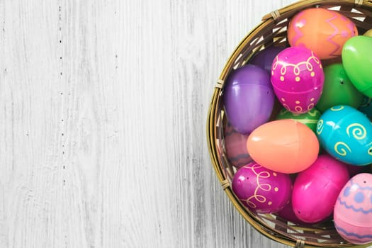 Easter eggs in basket on white wooden background