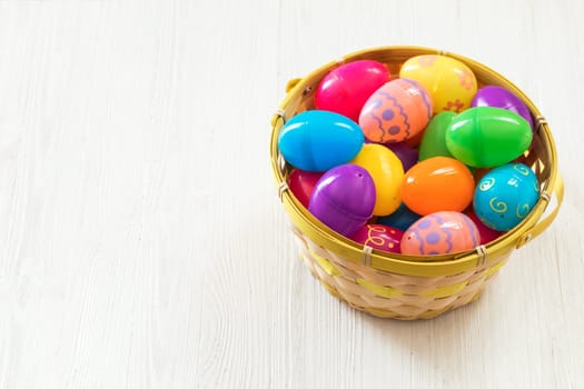 Easter eggs in basket on white wooden background
