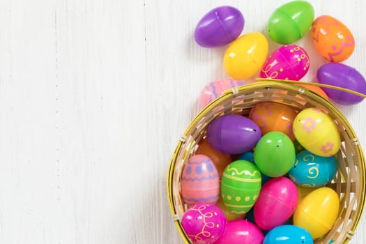 Easter eggs in basket on white wooden background