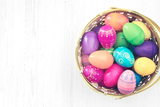 Easter eggs in basket on white wooden background