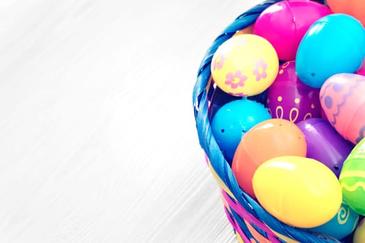 Easter eggs in basket on white wooden background