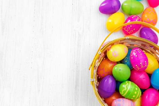 Easter eggs in basket on white wooden background
