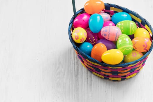 Easter eggs in basket on white wooden background