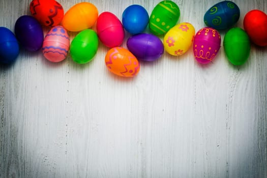 Multi colored Easte eggs on white wooden background