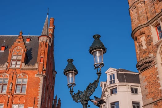 Street with old houses, lantern, Bruges, Belgium. Traditional Flemish medieval architecture in historic town centre. Brick houses in center of city. Typical belgian facades of retro vintage buildings