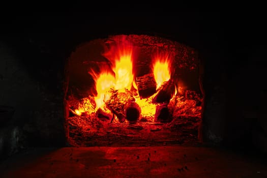 Firewood burning in brick oven, fire flame closeup. Flame on burning wood in stone fireplace from firebricks
