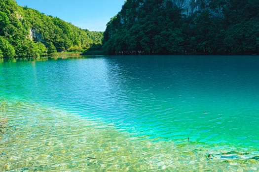 Plitvice Lakes National Park, Croatia, Europe. Natural park with waterfalls and turquoise water. UNESCO World Heritage site. Blue clear water of Plitvicka Jezera. View of lake, hills. Summer landscape