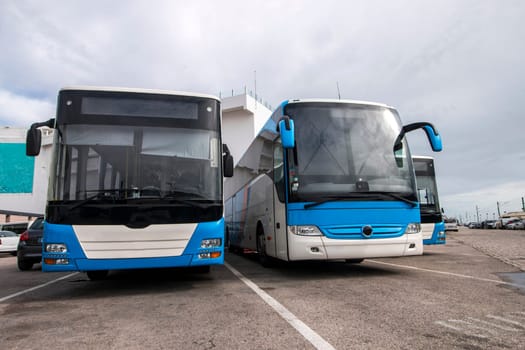 View of several blue and white Buses parked in the city.