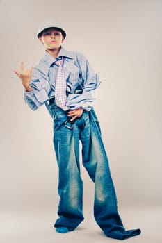 Caucasian boy wearing his Dad's shirt, jeans and tie on light background. He is wearing big adult size clothes which are too big for him.