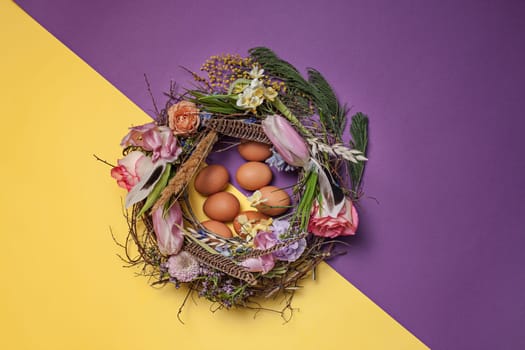 Easter card. Painted Easter eggs in nest on yellow table background. Top view of easter decoration. Happy easter concept