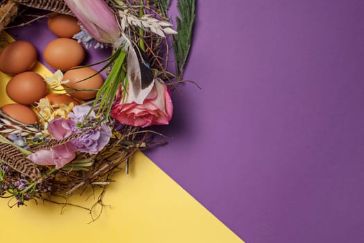 Easter card. Painted Easter eggs in nest on yellow table background. Top view of easter decoration. Happy easter concept