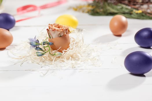 Beautiful easter table setting composition. A row of lilac and yellow color eggs on white wooden table background. Happy Easter greeting card. Side view