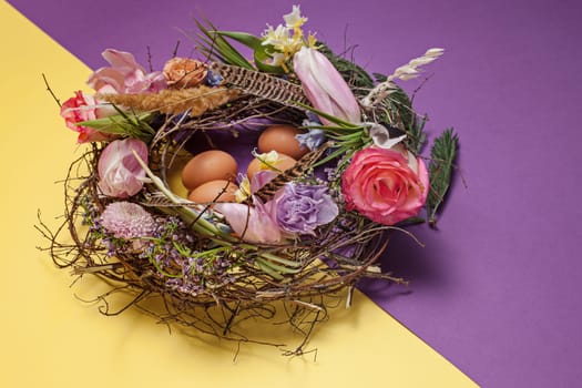 Easter card. Painted Easter eggs in nest on yellow table background. Side view of easter decoration. Happy easter concept