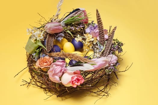 Easter card. Painted Easter eggs in nest on yellow table background. Side view of easter decoration. Happy easter concept