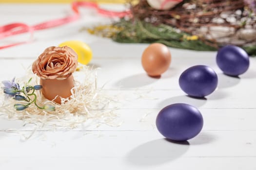Beautiful easter table setting composition. A row of lilac and yellow color eggs on white wooden table background. Happy Easter greeting card. Side view