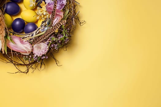 Easter card. Painted Easter eggs in nest on yellow table background. Top view of easter decoration. Happy easter concept. Trendy colors