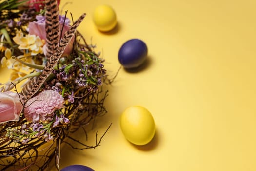 Easter card. Painted Easter eggs in nest on yellow table background. Top view of easter decoration. Happy easter concept. Trendy colors