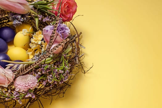Easter card. Painted Easter eggs in nest on yellow table background. Top view of easter decoration. Happy easter concept