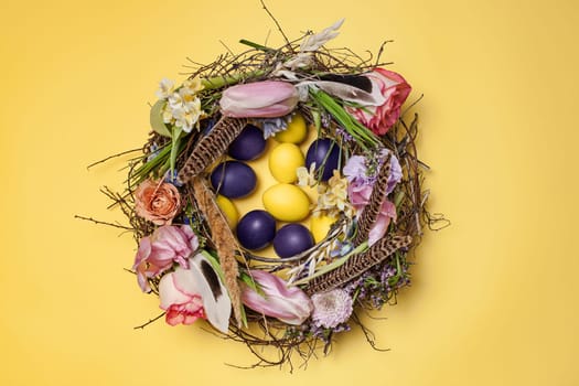 Easter card. Painted Easter eggs in nest on yellow table background. Top view of easter decoration. Happy easter concept. Trendy colors