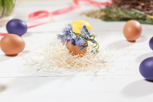 Beautiful easter table setting composition. A row of lilac and yellow color eggs on white wooden table background. Happy Easter greeting card. Side view
