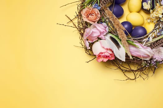 Easter card. Painted Easter eggs in nest on yellow table background. Top view of easter decoration. Happy easter concept. Trendy colors
