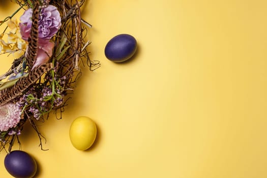 Easter card. Painted Easter eggs in nest on yellow table background. Top view of easter decoration. Happy easter concept. Trendy colors
