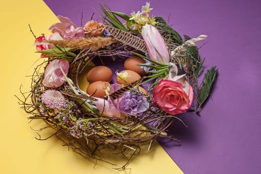 Easter card. Painted Easter eggs in nest on yellow table background. Side view of easter decoration. Happy easter concept