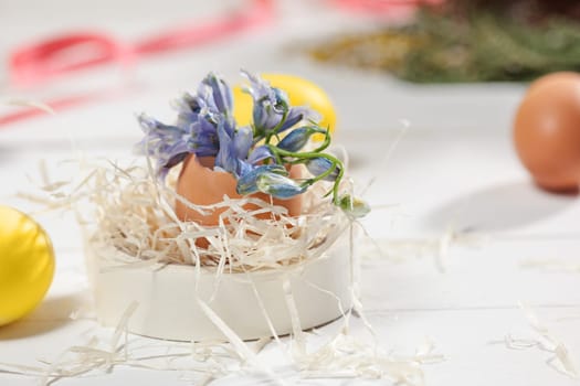 Beautiful easter table setting composition. A row of lilac and yellow color eggs on white wooden table background. Happy Easter greeting card. Side view