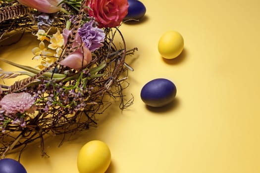 Easter card. Painted Easter eggs in nest on yellow table background. Top view of easter decoration. Happy easter concept. Trendy colors