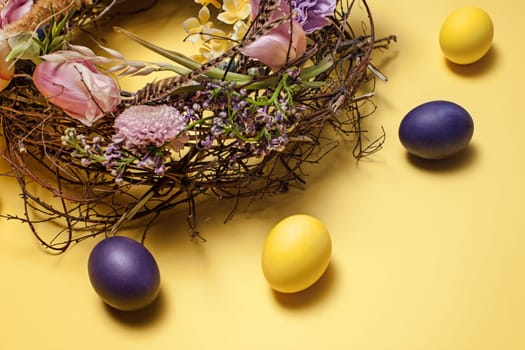 Easter card. Painted Easter eggs in nest on yellow table background. Top view of easter decoration. Happy easter concept. Trendy colors