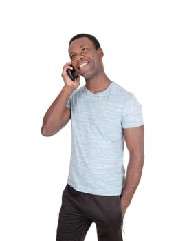 An handsome African American man standing in a gray t-shirt .talking at his cell phone and smiles, isolated for white background.