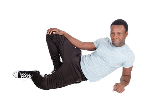 A young good looking African American man sitting on the floor,.resting, in truck pants and t-shirt, isolated for white background.