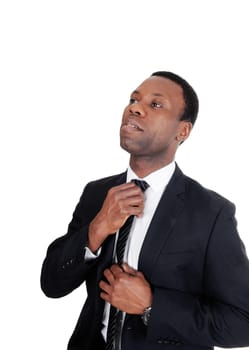 A handsome African American businessman standing in a dark suit.fixing his tie with booths hands, isolated foe white background.