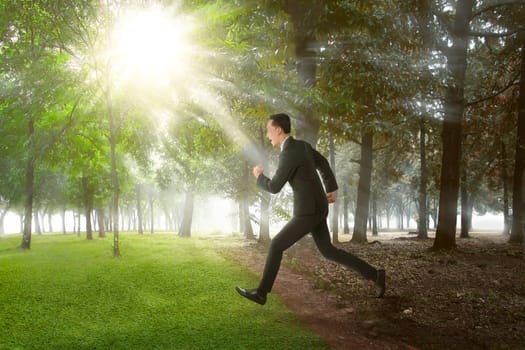 Happy asian businessman running on summer field on sunny day
