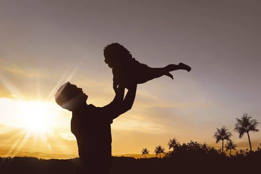 Silhouette of happy father and little girl playing together at sunset