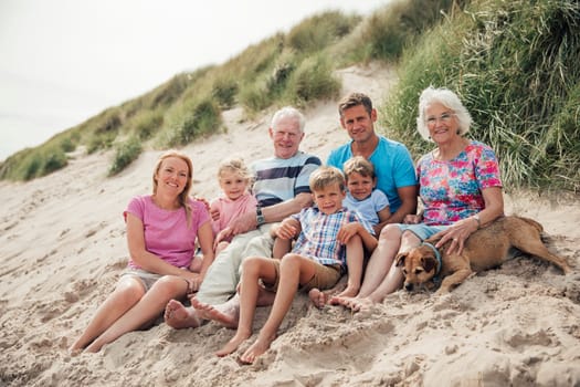 Family getting their photo taken as they sit all together on a sand dune.