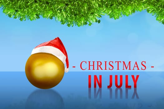 Golden christmas ball with santa hat on Christmas in July over blue background