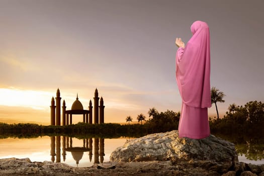 Rear view of asian muslim woman with headscarf praying during sunset background