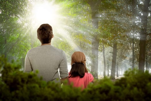 Back view of daughter and father relaxing together on the park