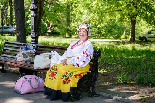 Kharkiv, Ukraine - May 03, 2014: Ukrainian woman with ethnic dress sitting on a bench and smile to the photographer
