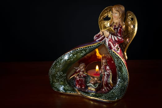 Nice ceramic crib on wood table and black background, with Angel on top