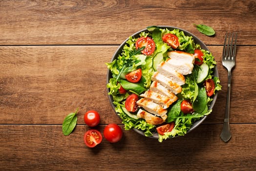 Fresh green salad with chicken breast and tomato.